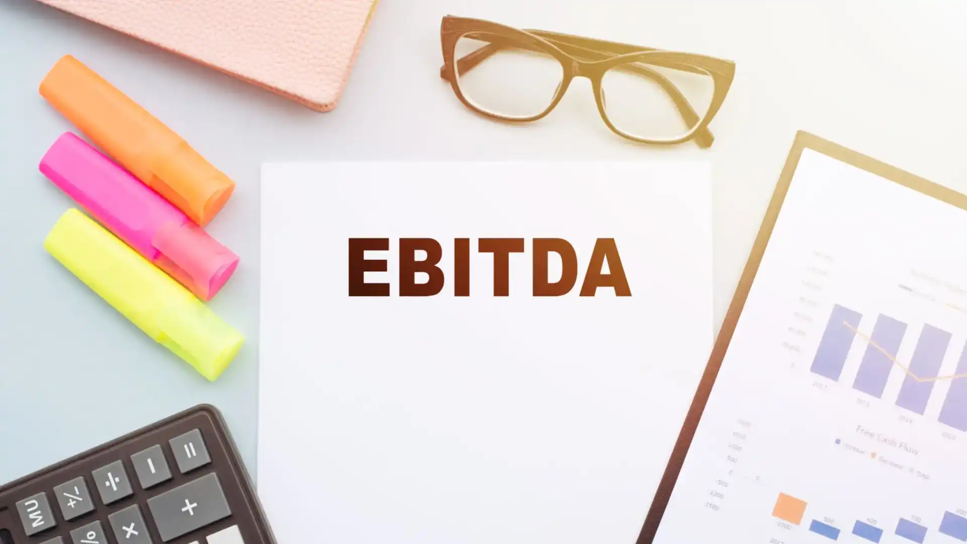 A paper with 'EBITDA' written, surrounded by office supplies.