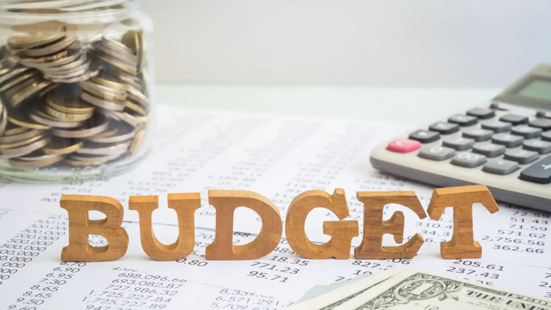 Wooden letters spelling BUDGET on financial papers with a calculator.