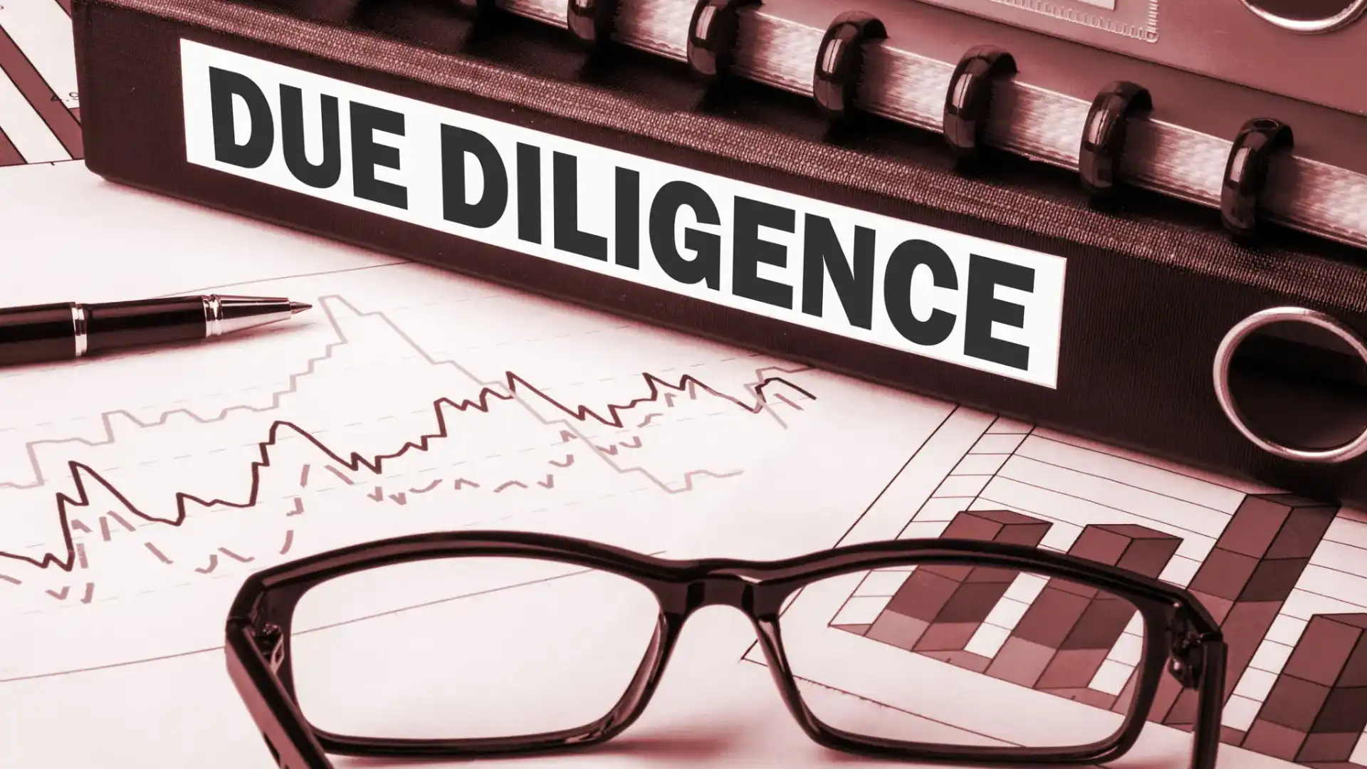 Close-up of glasses on a document titled 'Due Diligence' with financial charts.
