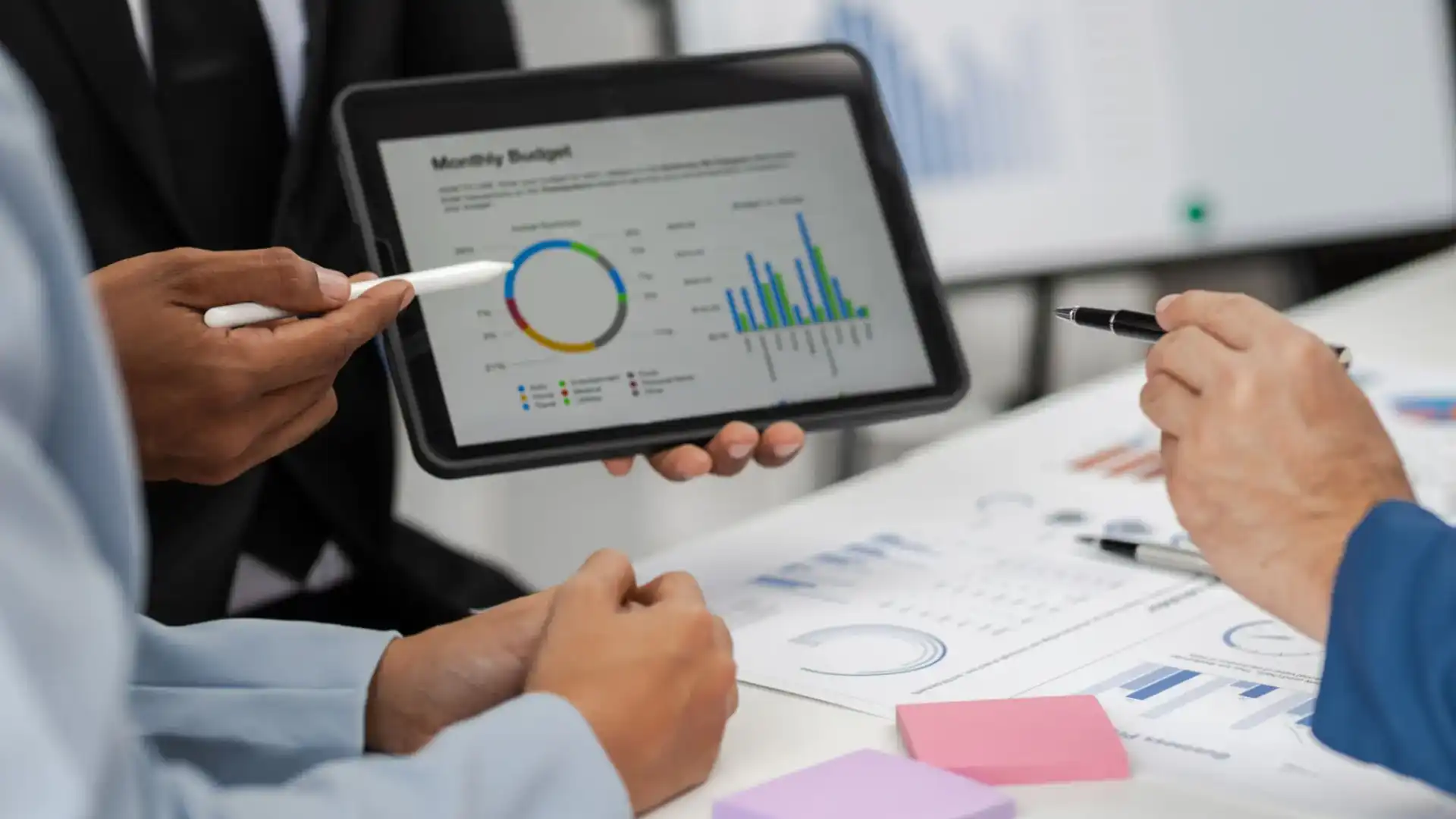 Person analyzing business data on a tablet with charts and graphs.