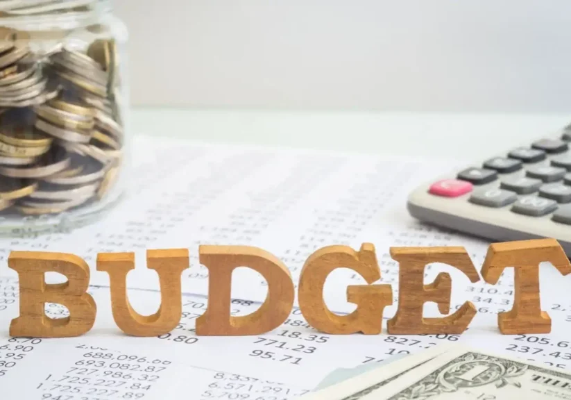 Wooden letters spelling BUDGET on financial papers with a calculator.