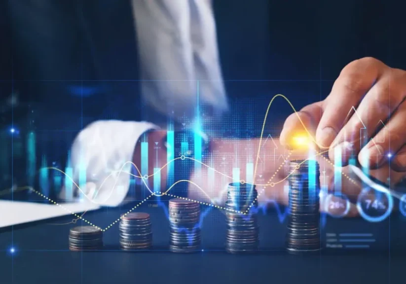Hand stacking coins with digital financial graphs overlay.