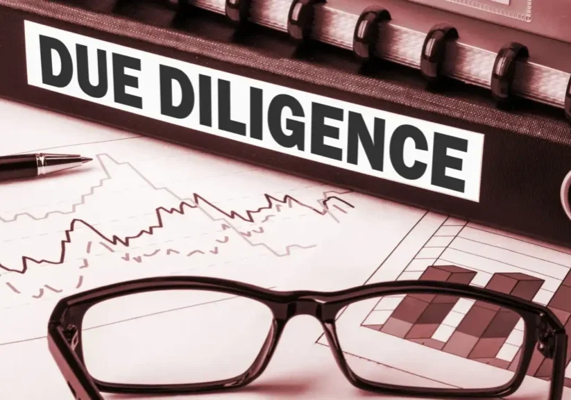 Close-up of glasses on a document titled 'Due Diligence' with financial charts.