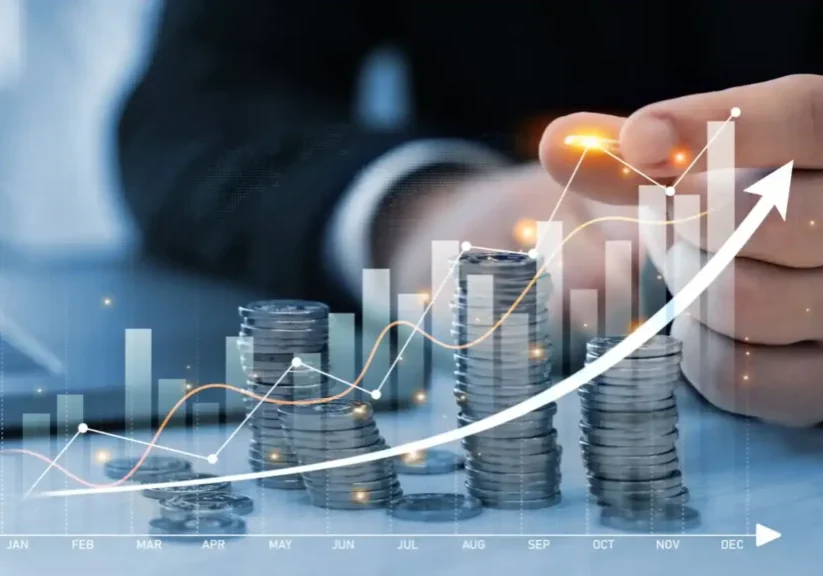 Stacks of coins with rising financial graph and businessman in background.