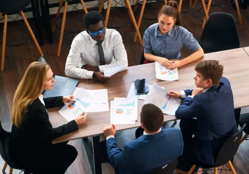 A group of professionals discussing documents around a table.
