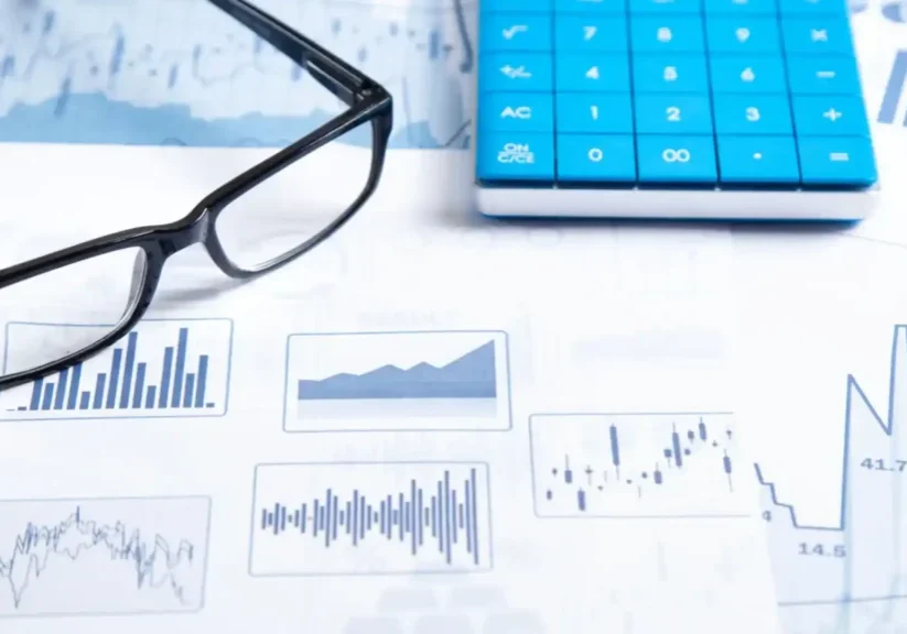Glasses, graphs, and calculator on a desk for data analysis.