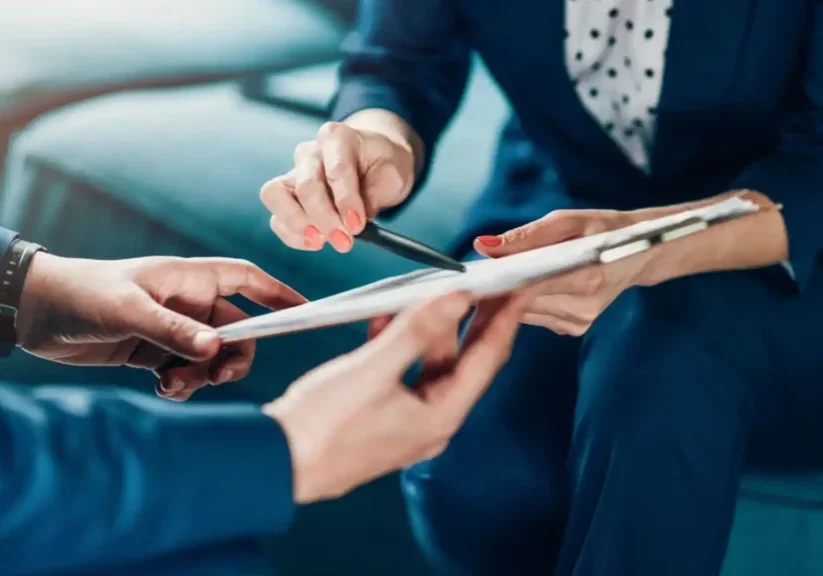 Two business professionals discussing documents with a pen and tablet.