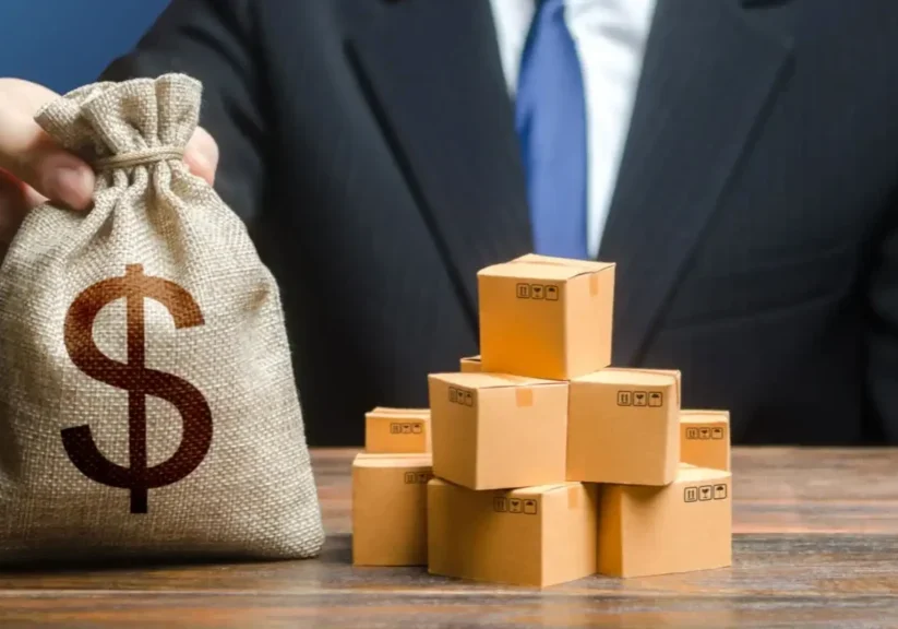 Businessman with money bag and stacked boxes symbolizing wealth.